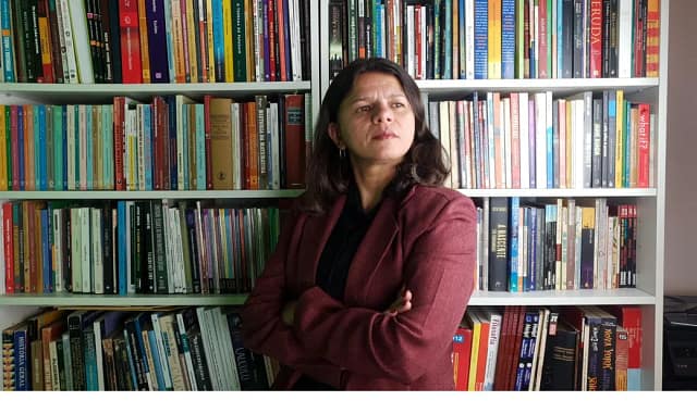 Profª Dra. Lessandra Marcelly diante de uma estante de livros de matemática